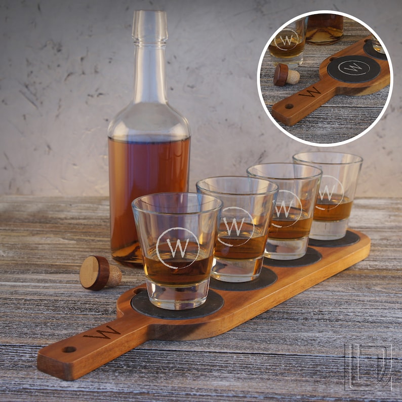 May include: A wooden serving tray with four shot glasses and a bottle of spirits. The glasses and tray are engraved with the letter "W".