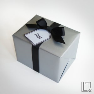 May include: A silver gift box with a black ribbon and bow. A white gift tag with black lettering reads "Jason".
