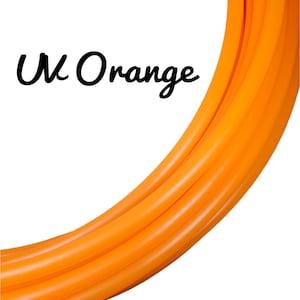 Puede incluir: Tubo de color naranja brillante en una disposición curva sobre un fondo blanco. El texto "UV Orange" está escrito en cursiva negra. El tubo parece liso y de color uniforme.