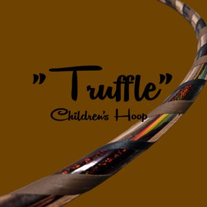 Könnte beinhalten: Ein brauner Kinderreifen mit dem Wort "Truffle" in schwarzer Schrift. Der Reifen hat ein braunes und beiges Streifenmuster mit Abschnitten mit farbenfrohen Akzenten und rotem Glitzer.