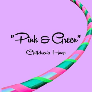 Könnte beinhalten: Ein Kinder-Hula-Hoop-Reifen in Rosa, Grün und schillernd. Der Reifen ist mit spiralförmigen rosa und grünen Bändern verziert. Der Text "Pink & Green" und "Children's Hoop" wird auf einem lila Hintergrund angezeigt.