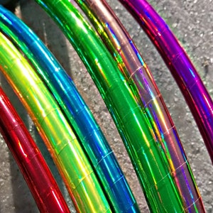 Puede incluir: Cinco aros iridiscentes de diferentes colores, incluyendo rojo, verde, azul y morado. Los aros están hechos de plástico y tienen un acabado brillante y reflectante.