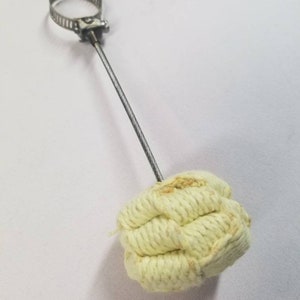 May include: A metal clamp attached to a wire with a yellow woven fire starter at the end.