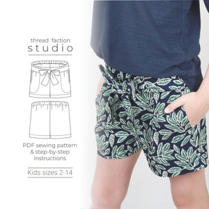 May include: A sewing pattern for kids shorts with a bow detail. The pattern includes instructions for sizes 2-14. The image shows a child wearing a pair of shorts made from the pattern.