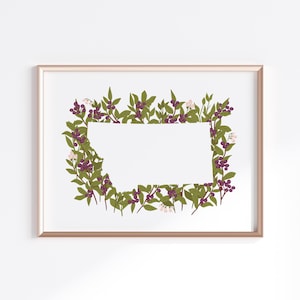 May include: A framed print featuring a rectangular white space surrounded by a botanical border. The border is composed of green leaves, purple berries, and small white flowers, all set against a white background. The frame is a light gold color.