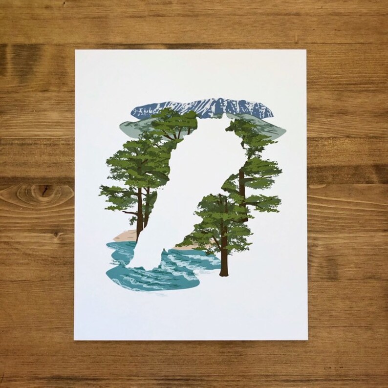 May include: A white silhouette of a person standing in front of a mountain landscape with trees and a river. The silhouette is surrounded by green trees and a blue river.