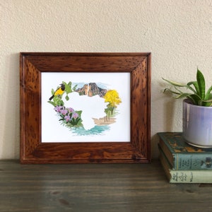 May include: A framed print of a yellow bird perched on a branch with a mountain range in the background. The image is surrounded by a white border and a brown wooden frame.