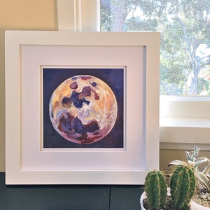 May include: A framed painting of a purple, yellow, and white moon on a dark blue background.