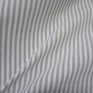 Puede incluir: Una pieza de tela con un patr&oacute;n repetitivo de rayas verticales en tonos alternos de gris claro y blanco. El tejido muestra pliegues y drapeados suaves, creando un efecto de onda sutil a trav&eacute;s de la superficie del material.