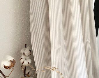 May include: A close-up of a beige and white striped curtain with a natural cotton branch in the foreground.