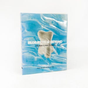 May include: A book titled "BLOBJECTS & BEYOND" with the subtitle "THE NEW FLUIDITY IN DESIGN." The cover features a light blue background with a white, abstract shape. The author's names, STEVEN SKOV HOLT and MARA HOLT SKOV, are at the bottom.