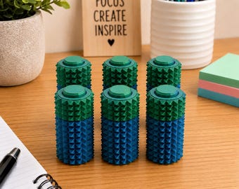Puede incluir: Seis herramientas sensoriales cilíndricas dispuestas en dos filas de tres. Cada herramienta presenta una superficie texturizada con pequeñas puntas piramidales en relieve. La mitad superior es verde, la mitad inferior es azul, con una parte superior plana.