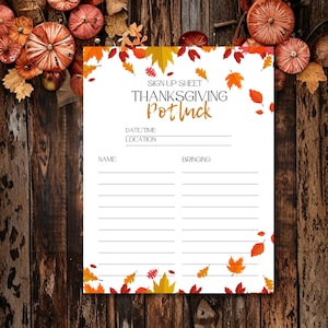 May include: A white Thanksgiving potluck sign-up sheet with fall leaf and pumpkin decorations. The sign reads "SIGN UP SHEET THANKSGIVING Potluck" with spaces for date, time, location, name, and what to bring. The background is a wooden surface.
