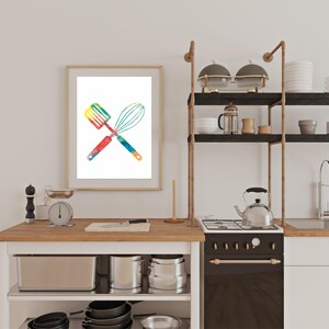 May include: A framed watercolor print of a spatula and whisk crossed over each other. The utensils are painted in a rainbow of colors.