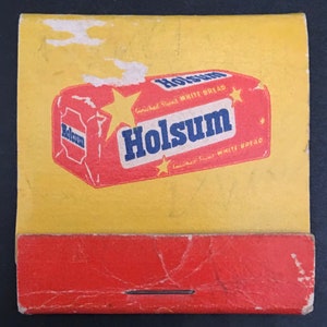 May include: A vintage matchbook cover with a yellow background and red border. The cover features a cartoon illustration of a loaf of bread with the text "Enriched Sliced White Bread Holsum" printed on the front.