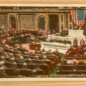 May include: A black and white vintage postcard depicting the House of Representatives in Washington, D.C. The image shows a large room filled with people seated in rows of chairs. An American flag hangs above the speaker's podium.