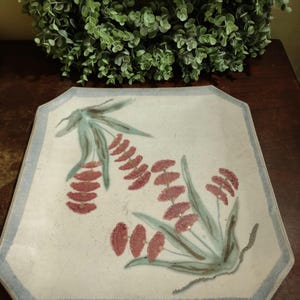 May include: A square ceramic serving platter with a light blue border and a white background. The platter features a hand-painted design of stylized green leaves and red flowers.