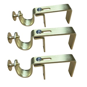 May include: Three gold metal curtain rod brackets with a screw and a round cap. The brackets are designed to hold a curtain rod.