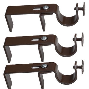 May include: Three brown metal curtain rod brackets with a screw on the end. The brackets are designed to hold a curtain rod.