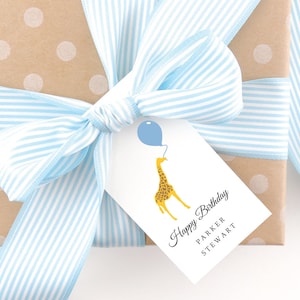 May include: A gift wrapped in brown paper with white polka dots and tied with a blue and white striped ribbon. A gift tag with a giraffe holding a blue balloon is attached to the ribbon. The tag reads "Happy Birthday Parker Stewart".