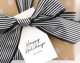 May include: A brown gift box with white polka dots is wrapped with a black and white striped ribbon. A white gift tag with black text reads "Happy Holidays" and "The Smiths".