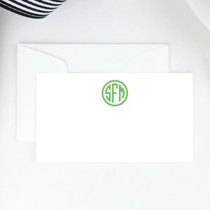 May include: A white card with a green circle monogram of the letters "SFM" in a simple, modern font.