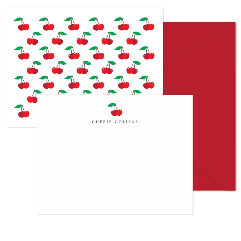May include: A white card with a red envelope. The card has a cherry pattern and the text "Cherie Collins" printed on it.
