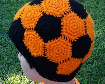 May include: A crocheted hat shaped like a soccer ball with black and orange panels.