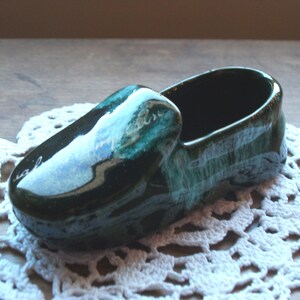 May include: A green and blue ceramic shoe-shaped trinket. The shoe is glazed with a mottled green and blue finish.