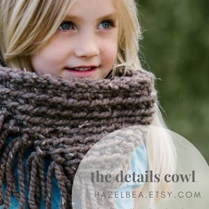 May include: A young person wearing a brown knit cowl with fringe. The cowl is thick and textured, with a neutral color palette. The text "the details cowl" is visible in a circular graphic.