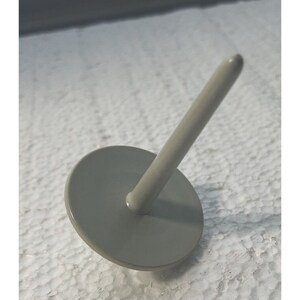 May include: A gray plastic spinning top with a rounded top and a flat base.