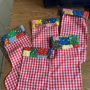 May include: Five red and white gingham Christmas stockings with colorful patchwork fabric at the top.