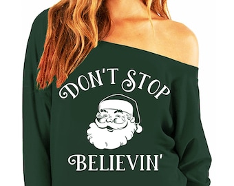 May include: A green off-the-shoulder sweatshirt with white text that reads "Don't Stop Believin'" and a white illustration of Santa Claus.