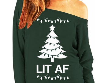 May include: Dark green off-the-shoulder sweatshirt with a white Christmas tree design and the text "LIT AF". The tree is decorated with white lights and a star. The sweatshirt has long sleeves.
