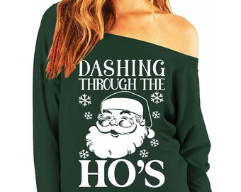 May include: Green off-the-shoulder sweatshirt with a white graphic of Santa Claus and the text "Dashing Through The Ho's".