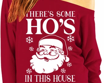 May include: Red off-the-shoulder sweatshirt with a white graphic of Santa Claus and the text "There's some Ho's in this house".