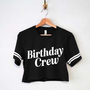 May include: Black cropped t-shirt with white lettering that says "Birthday Crew" and white stripes on the sleeves.