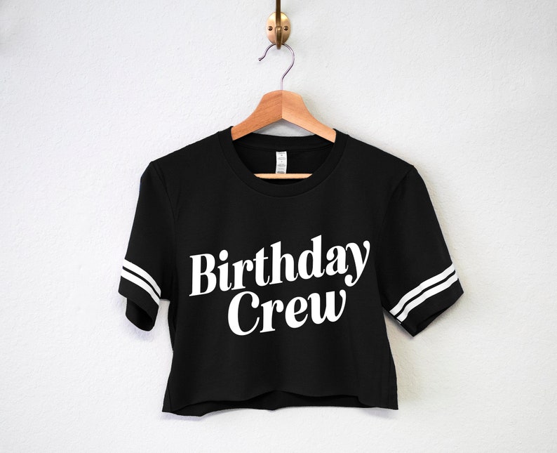 May include: Black cropped t-shirt with white lettering that says "Birthday Crew" and white stripes on the sleeves.