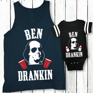 Op de afbeelding: Een bijpassend set van een marineblauw tanktop en een zwarte baby onesie met een witte afbeelding van Benjamin Franklin met een zonnebril en de tekst "Ben Drankin".