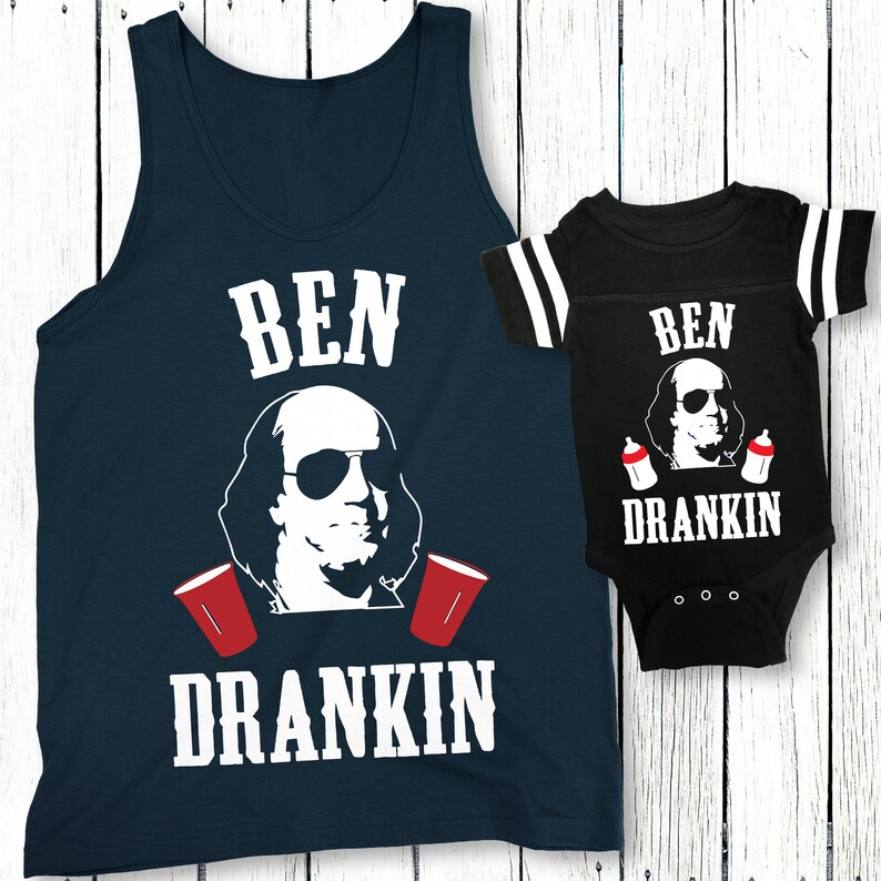 Op de afbeelding: Een bijpassend set van een marineblauw tanktop en een zwarte baby onesie met een witte afbeelding van Benjamin Franklin met een zonnebril en de tekst "Ben Drankin".