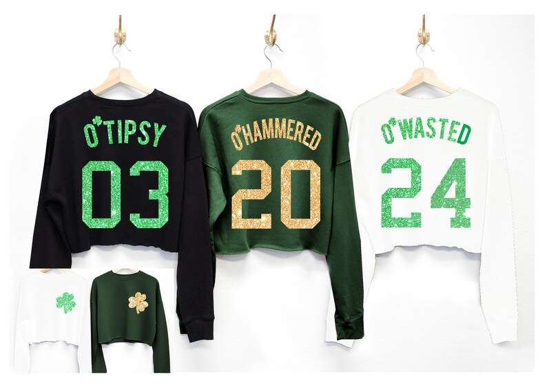 May include: Three cropped sweatshirts with green shamrock designs and gold glitter text. The black sweatshirt says "O'Tipsy 03", the green sweatshirt says "O'Hammered 20", and the white sweatshirt says "O'Wasted 24".