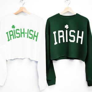 May include: Two long-sleeved cropped sweatshirts with a shamrock graphic and text. One sweatshirt is white with green text that says "IRISH-ISH". The other sweatshirt is green with white text that says "IRISH".