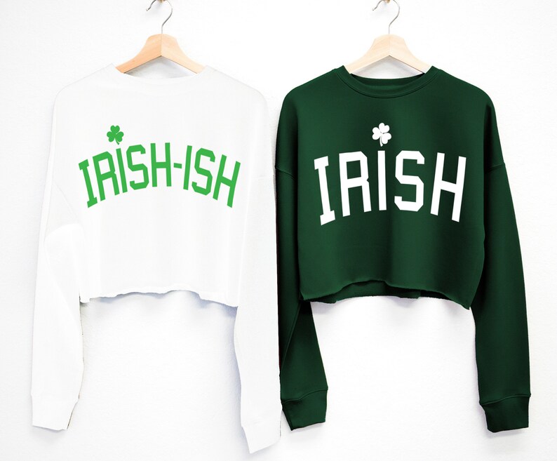 May include: Two long-sleeved cropped sweatshirts with a shamrock graphic and text. One sweatshirt is white with green text that says "IRISH-ISH". The other sweatshirt is green with white text that says "IRISH".
