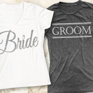 Puede incluir: Dos camisetas blancas con las palabras "Bride" y "Groom" impresas en ellas. La camiseta de la novia tiene un dise&ntilde;o de purpurina plateada y la camiseta del novio tiene un contorno blanco.