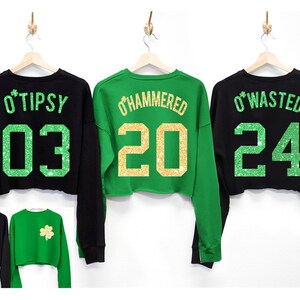 May include: Three black and green cropped sweatshirts with glitter text and numbers on the back. The sweatshirts say "O'Tipsy 03", "O'Hammered 20", and "O'Wasted 24".
