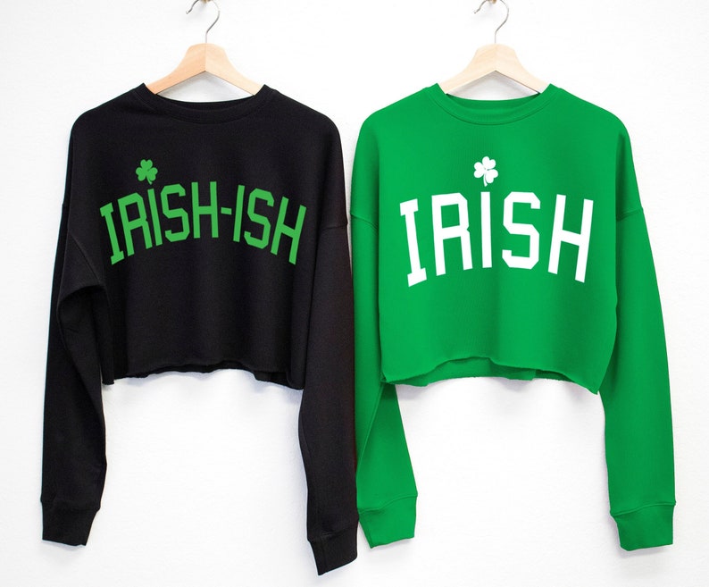May include: Two cropped sweatshirts with long sleeves. One is black with green text that says "IRISH-ISH" and a green shamrock. The other is green with white text that says "IRISH" and a green shamrock.
