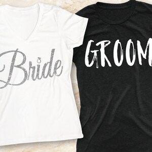 Puede incluir: Dos camisetas blancas con las palabras "Bride" y "Groom" impresas en ellas. La camiseta "Bride" tiene un dise&ntilde;o de purpurina plateada. La camiseta "Groom" tiene un fondo negro.