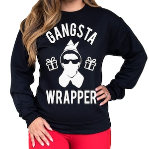 May include: Black sweatshirt with a white graphic of a Christmas elf wearing sunglasses and a Santa hat. The text "Gangsta Wrapper" is printed below the elf.