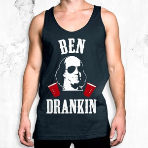 Op de afbeelding: Een marineblauw tanktop met een witte afbeelding van Benjamin Franklin met een zonnebril en rode plastic bekers. De tekst "BEN" en "DRANKIN" is in wit op het shirt gedrukt.