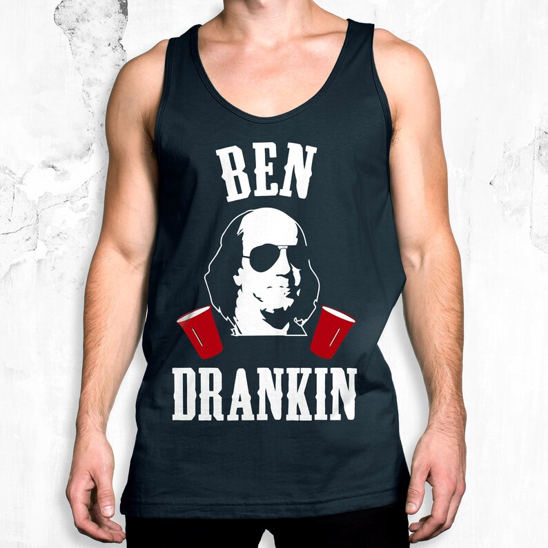 Op de afbeelding: Een marineblauw tanktop met een witte afbeelding van Benjamin Franklin met een zonnebril en rode plastic bekers. De tekst "BEN" en "DRANKIN" is in wit op het shirt gedrukt.